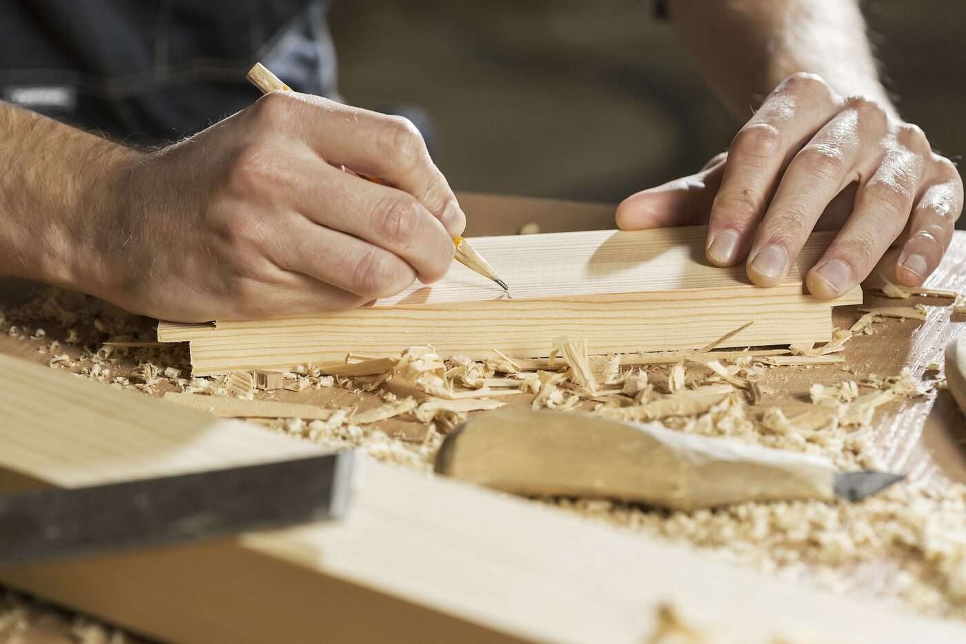 Hands marking a line on a timber board with a pencil